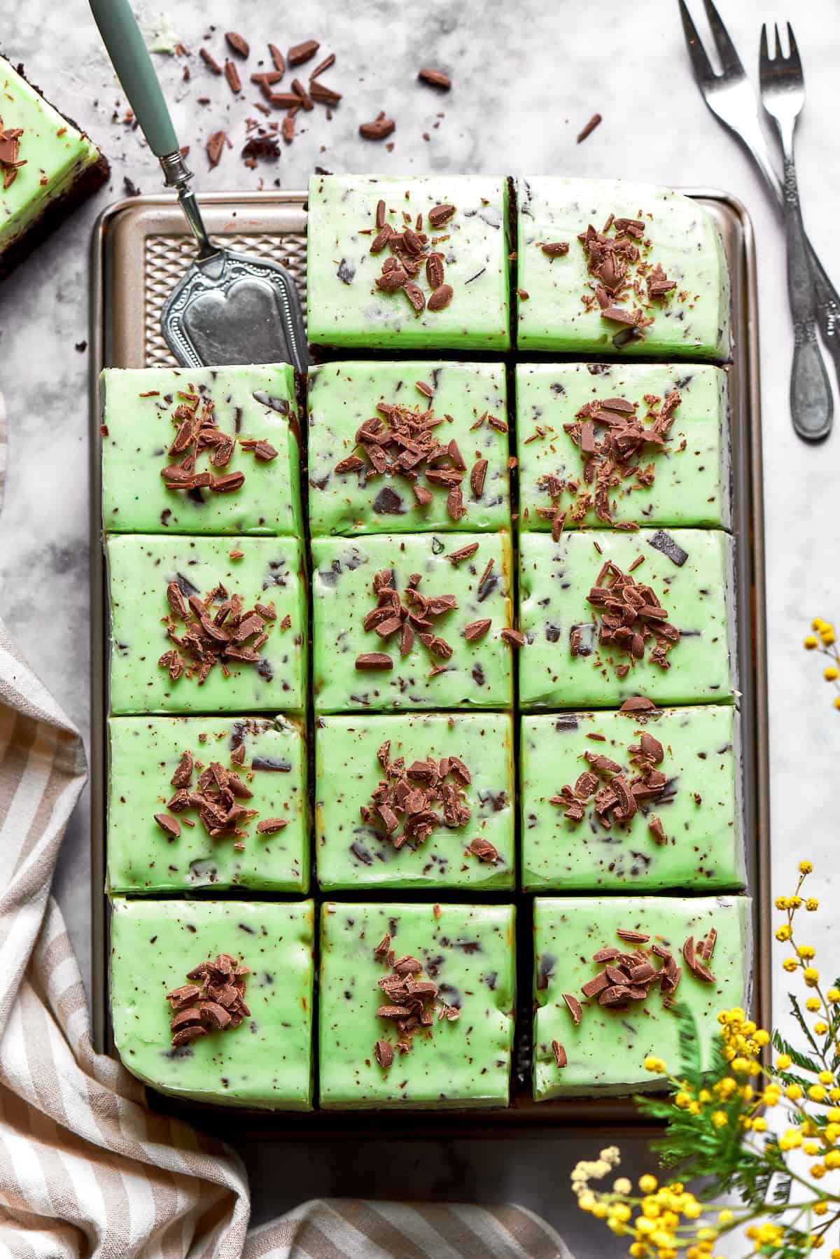 Chocolate cake with mint buttercream is perfect for any occasion. With fluffy mint frosting flecked with chocolate, it's such a crowd-pleaser! overhead photo of mint chocolate chip buttercream on cake that is cut into square pieces
