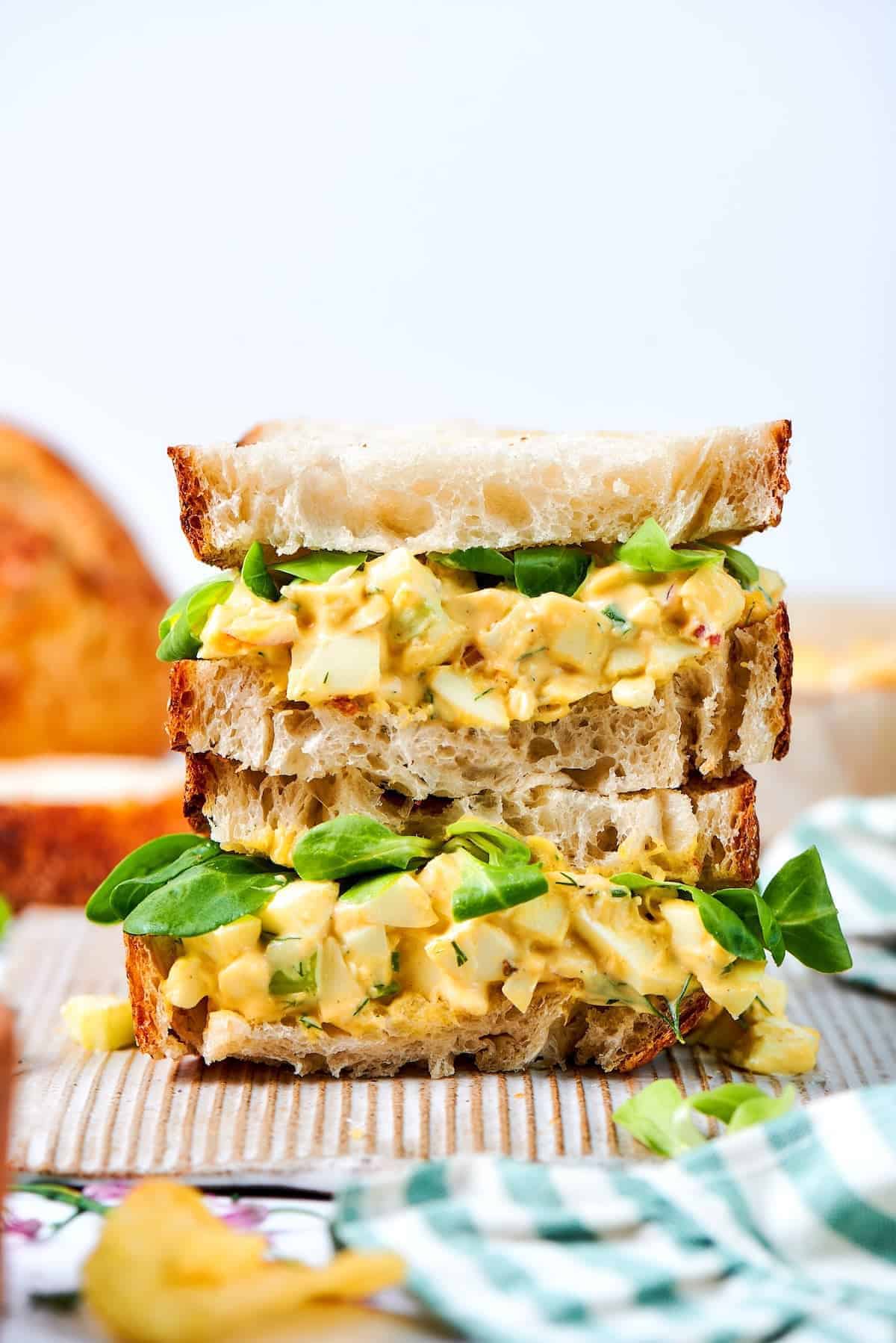 Creamy egg salad gets a fresh lift from bright herbs, making this egg salad sandwich a simple lunch that tastes anything but ordinary! close-up photo of a stack of egg salad sandwiches