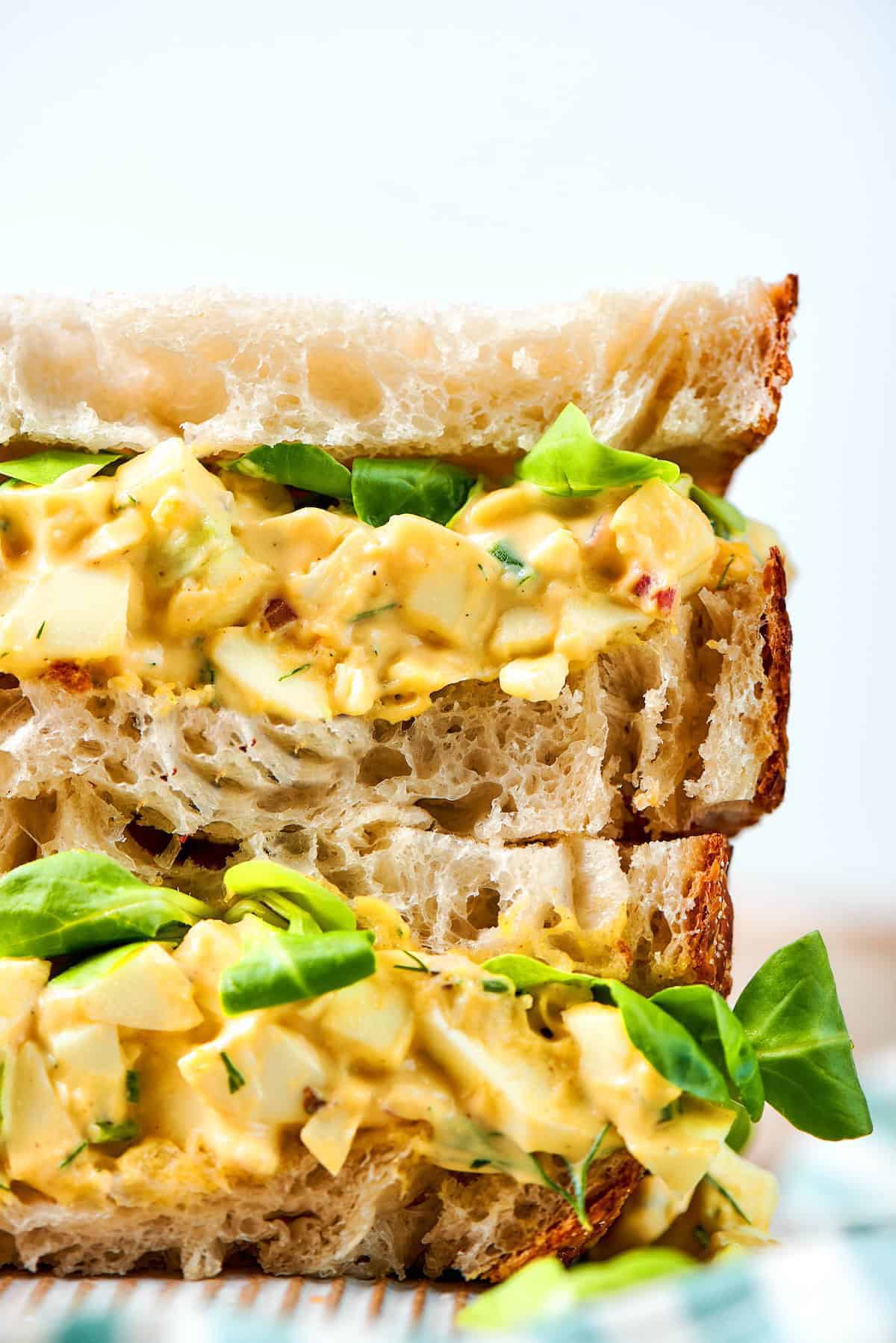 Creamy egg salad gets a fresh lift from bright herbs, making this egg salad sandwich a simple lunch that tastes anything but ordinary! close-up photo of a stack of egg salad sandwiches