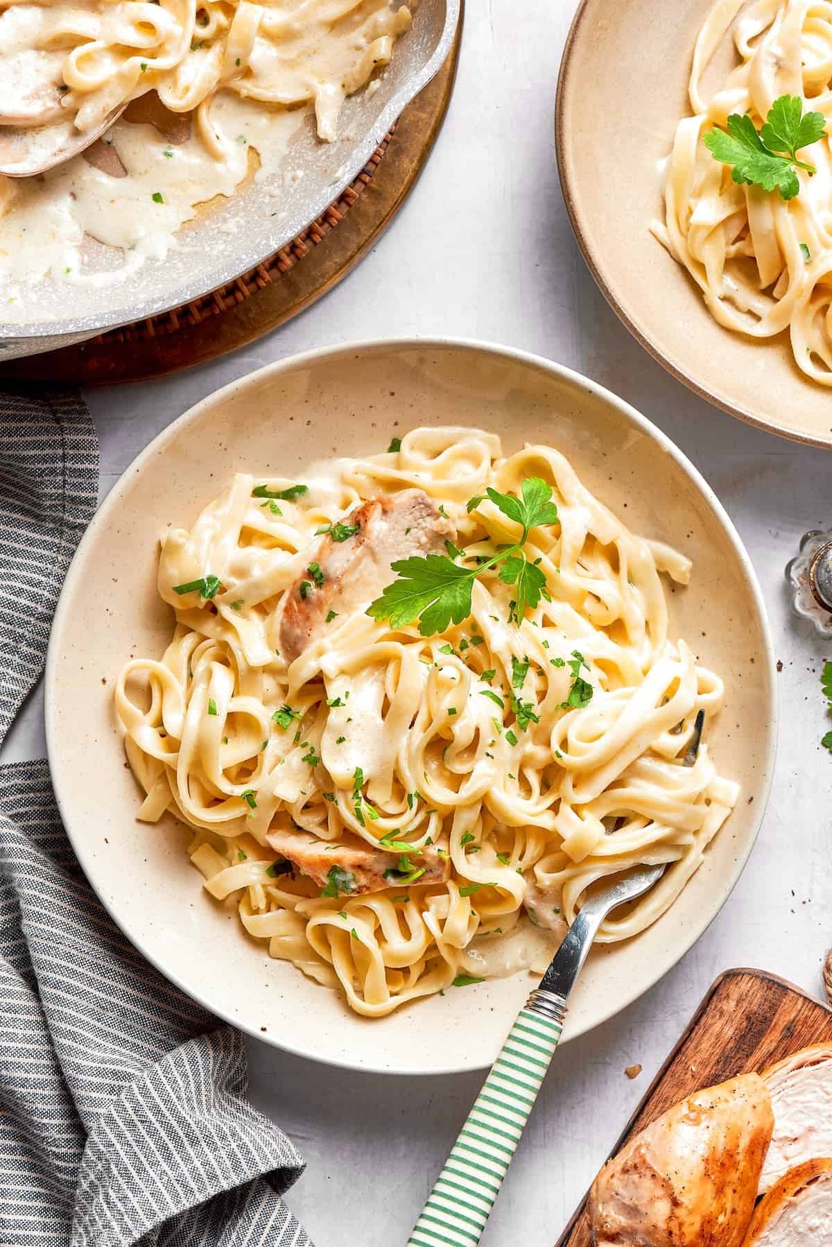 This chicken fettuccine Alfredo pairs chewy pasta with a garlicky Parmesan cream sauce and pan-fried chicken for a restaurant-worthy meal. Bowl of fettuccine alfredo with chicken.