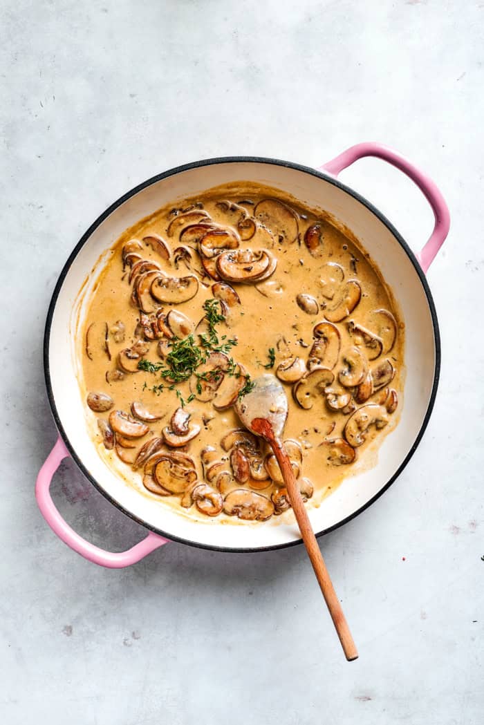 Fresh thyme added to skillet of mushroom sauce.