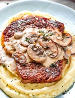 creamy mushroom sauce over a cooked steak on top of mashed potatoes
