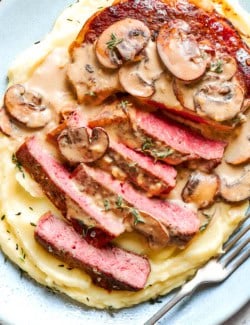 Sliced steak served over mashed potatoes with creamy mushroom sauce.