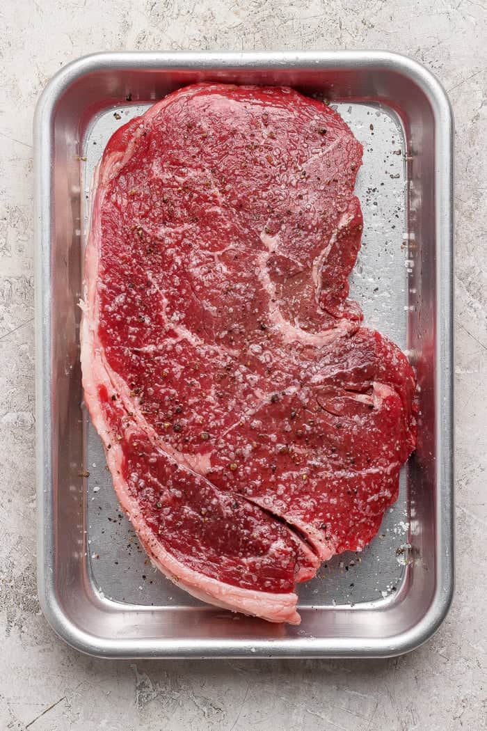 This cast iron skillet steak is tender and perfectly seared, with a rich garlic butter finish. The best way to cook steak on the stovetop! Seasoned steak on pan.