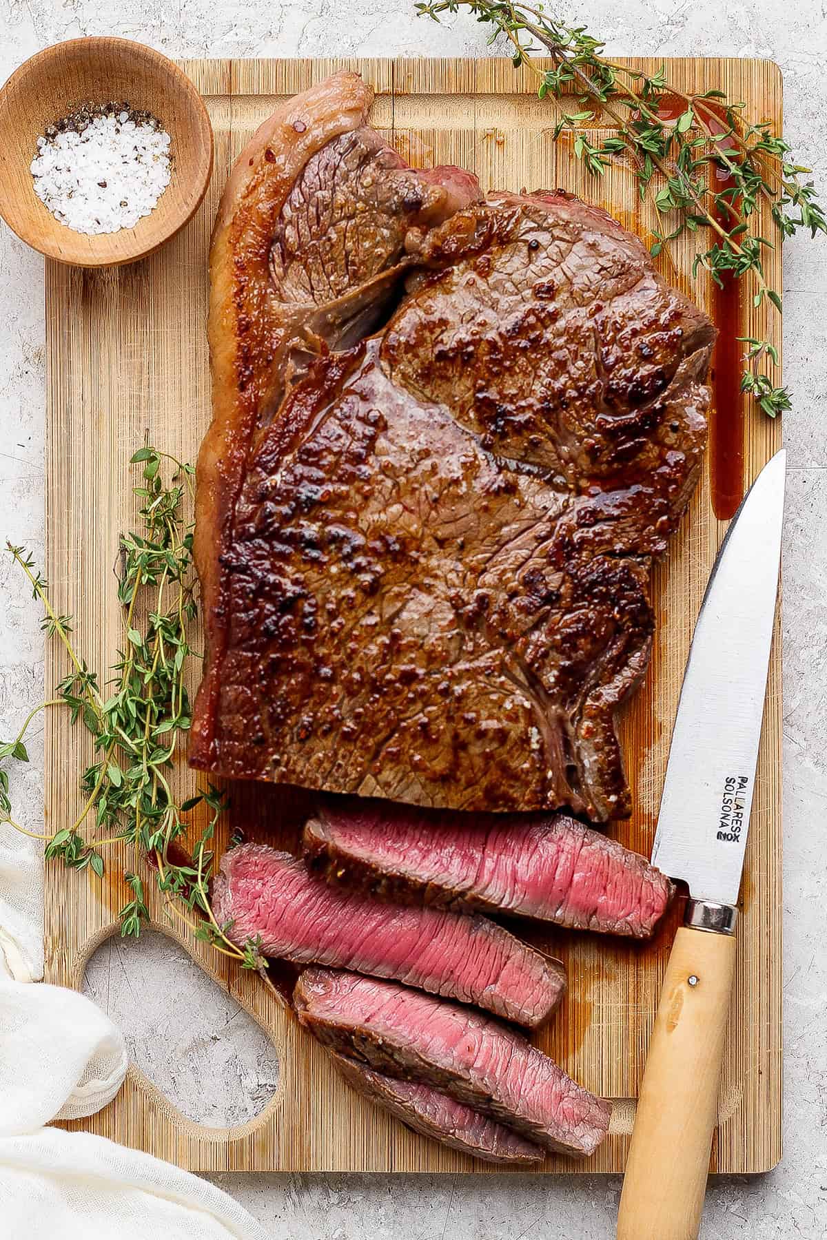 This cast iron skillet steak is tender and perfectly seared, with a rich garlic butter finish. The best way to cook steak on the stovetop! Cast iron skillet steak on board with 4 slices cut.