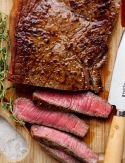 slicing steak on a wooden cutting board