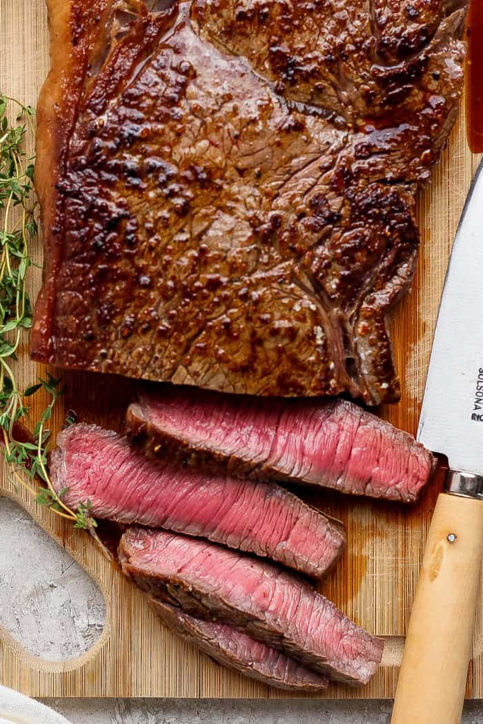 This cast iron skillet steak is tender and perfectly seared, with a rich garlic butter finish. The best way to cook steak on the stovetop! slicing steak on a wooden cutting board