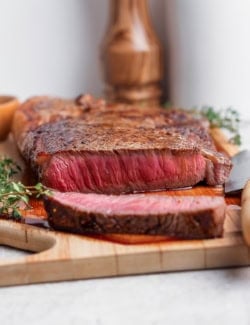 Cast iron skillet steak sliced on cutting board.