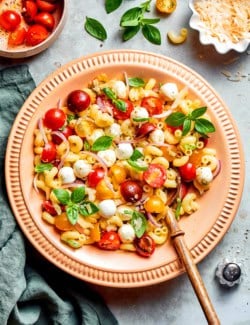 overhead photo of pasta caprese salad in a peach-colored serving bowl