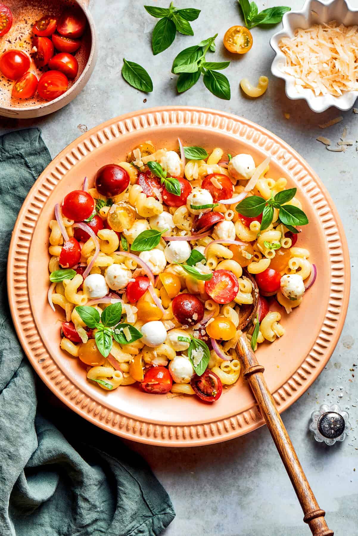 overhead photo of pasta caprese salad in a peach-colored serving bowl