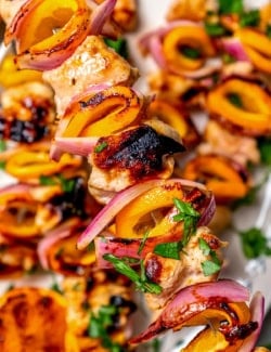 close-up photo of a grilled turkey kabob with orange slices, with more kabobs in the background
