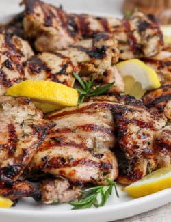 Grilled lemon chicken thighs on plate.