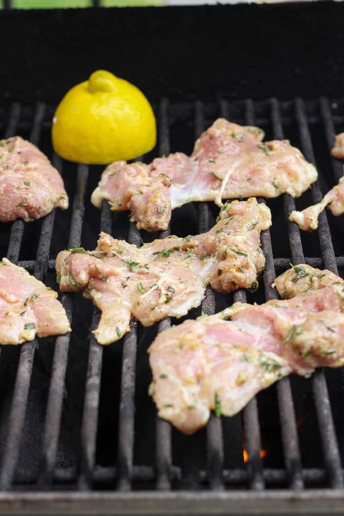 These grilled lemon chicken thighs are juicy and smoky, with a fresh lemon-herb marinade to brighten things up. The perfect summer main dish! Marinated chicken thighs on grill.