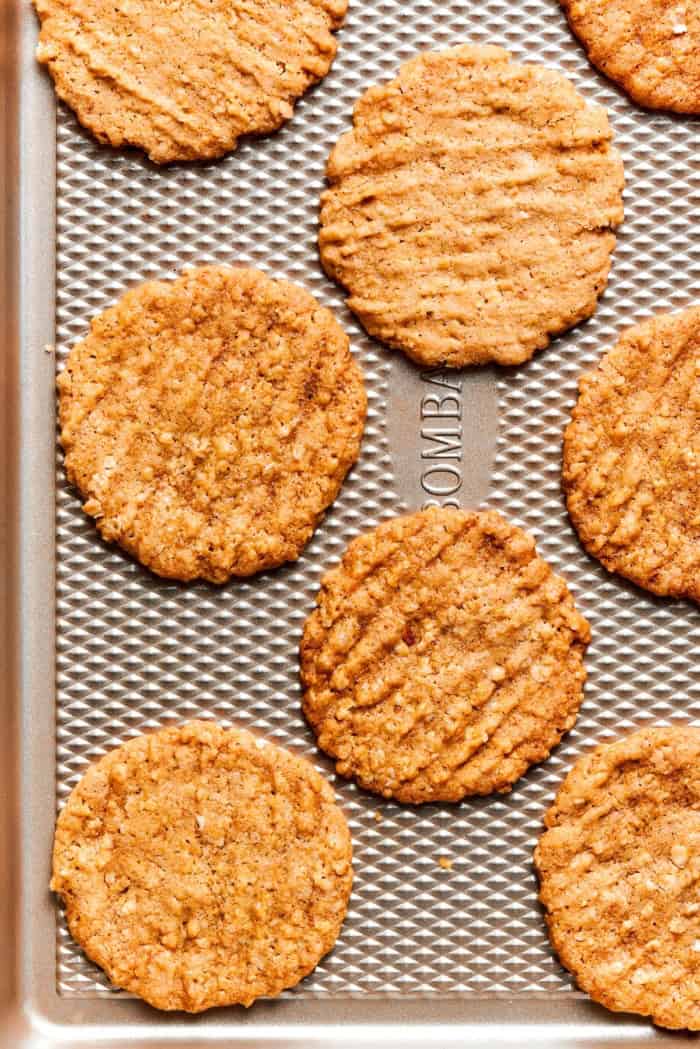 These thin, crispy oat cookies are buttery and golden on the edges, with the most delightful crunch. Made with simple pantry ingredients! Crispy oat cookies on textured baking sheet.