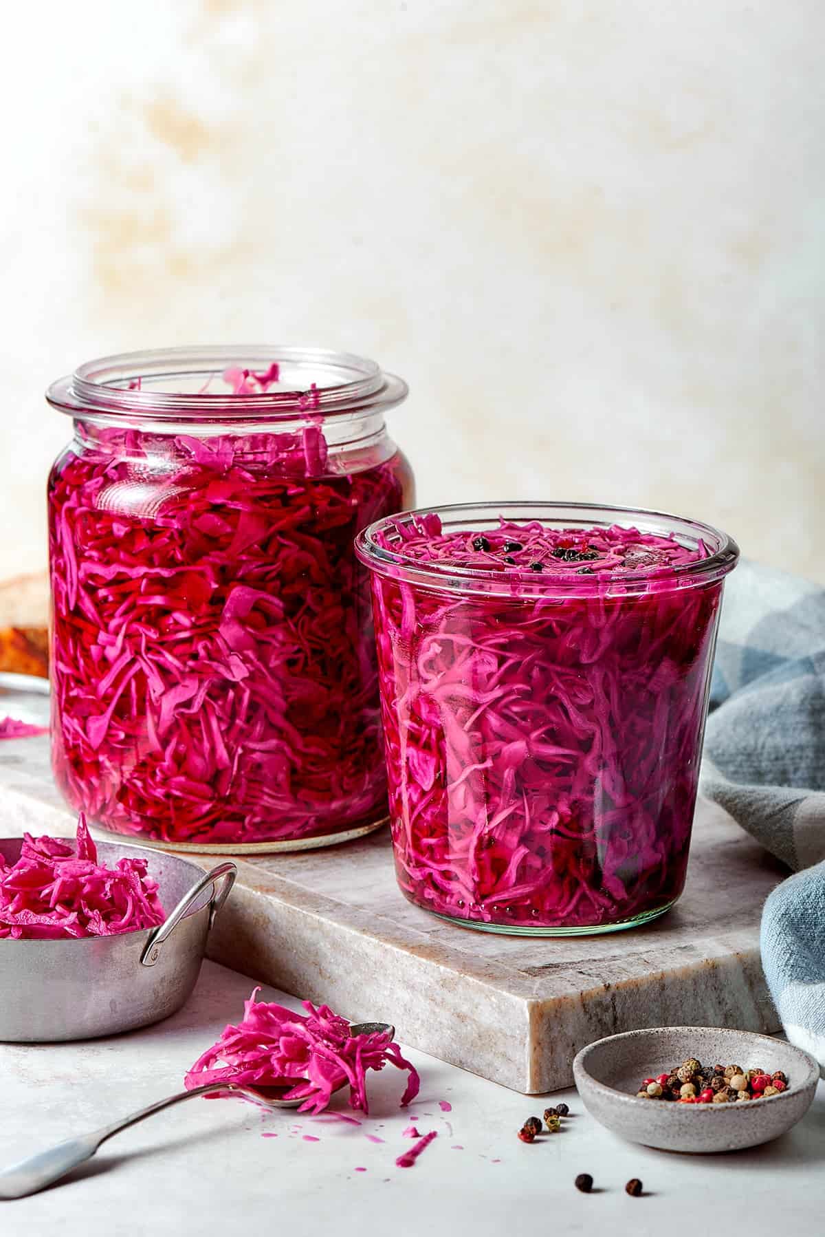 two jars of pickled red cabbage on a cutting board