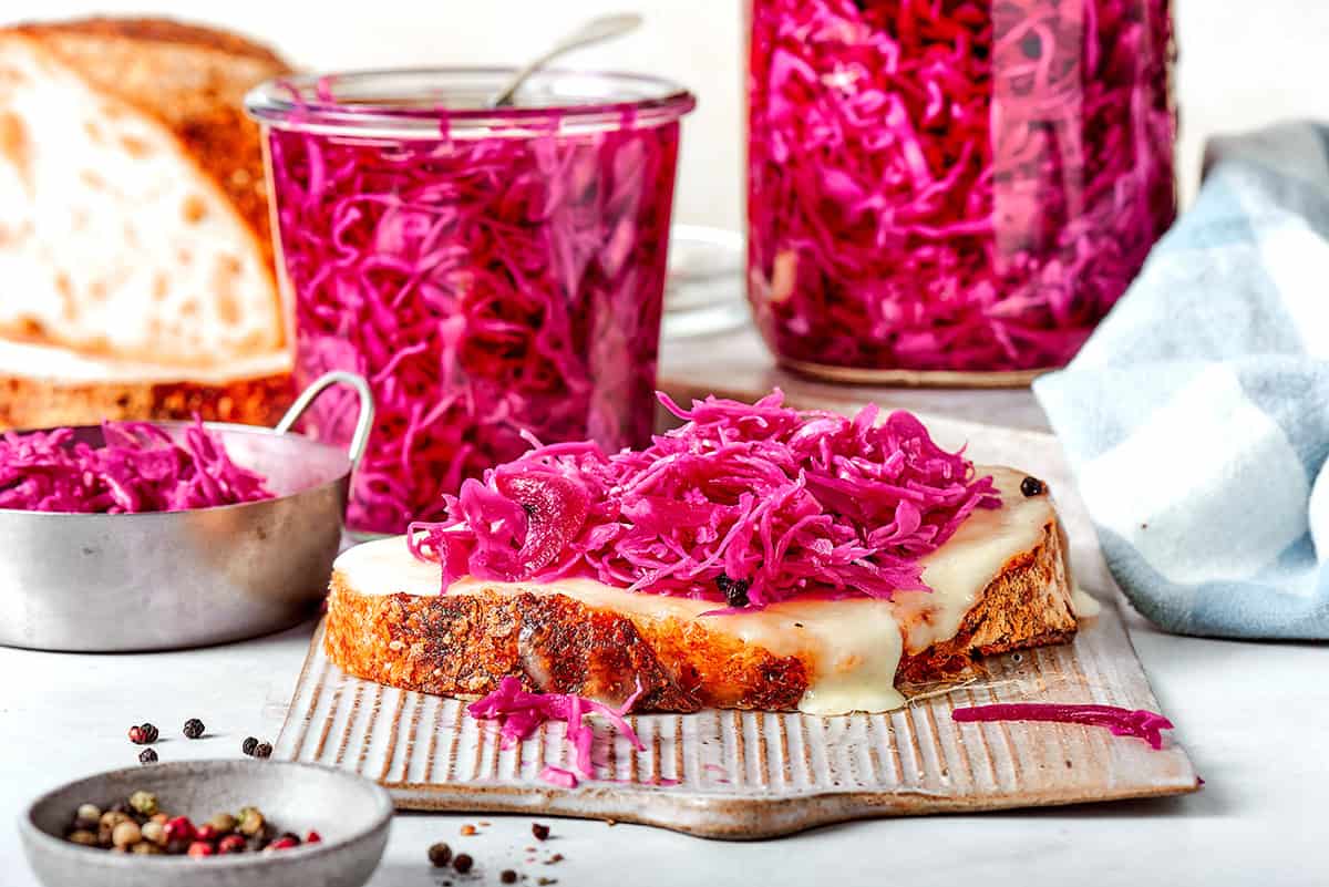 two jars of pickled red cabbage, plus a slice of toasted bread topped with melty cheese and pickled red cabbage